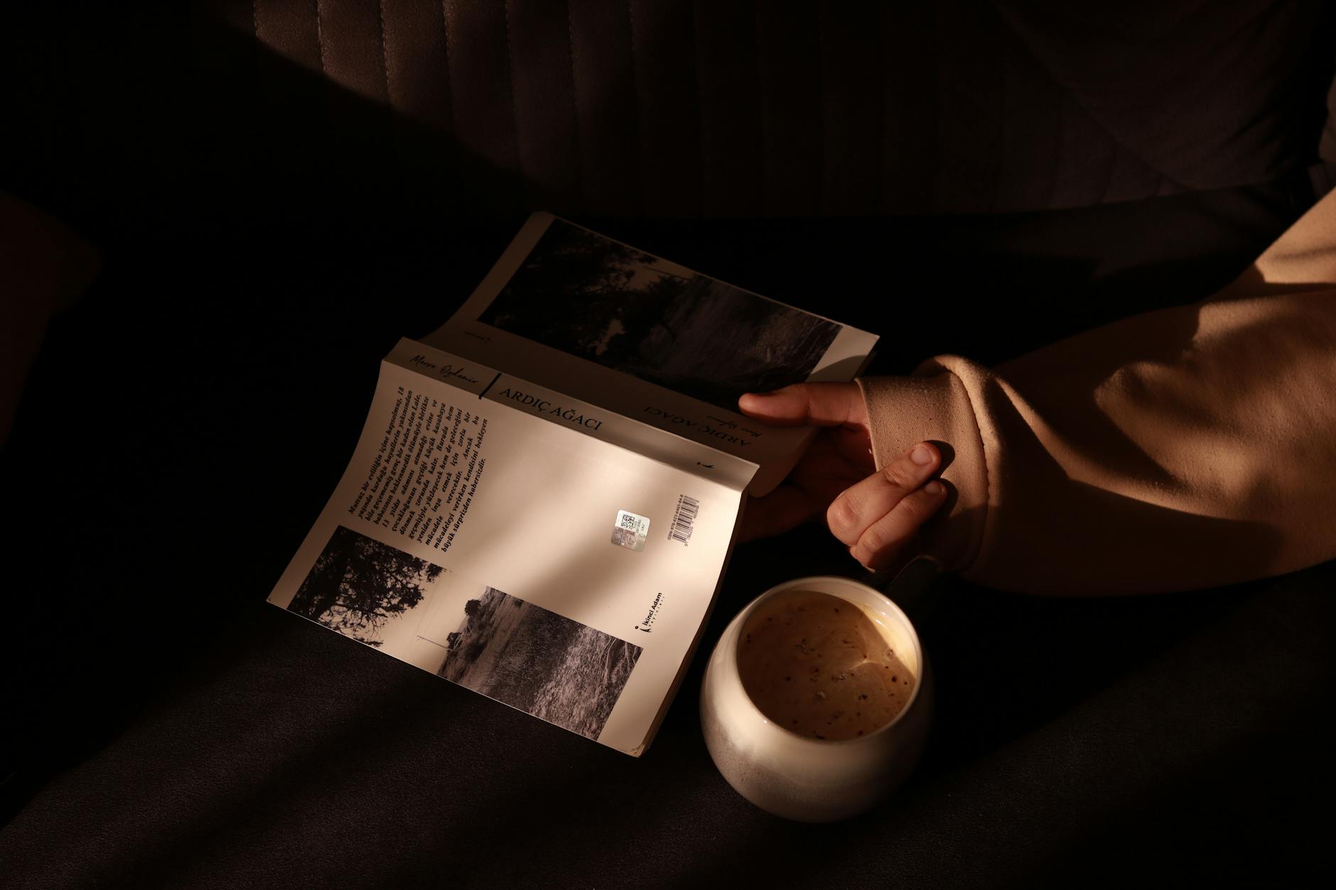 hand with book by cup of coffee