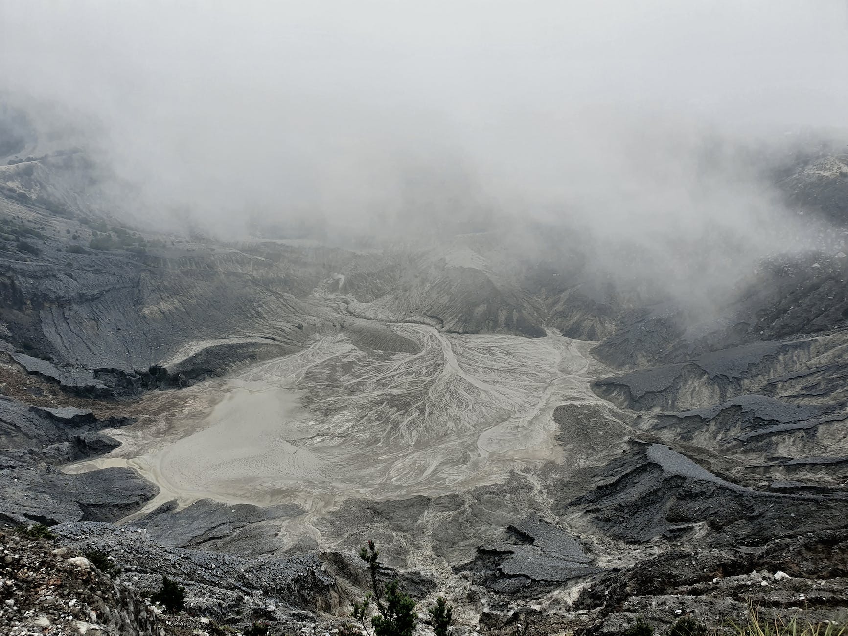 rough volcanic crater with foamy hot water in mist