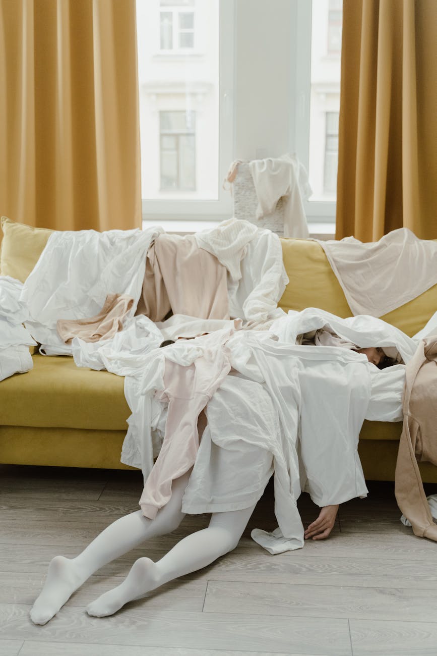 woman lying at the couch covered with clothes