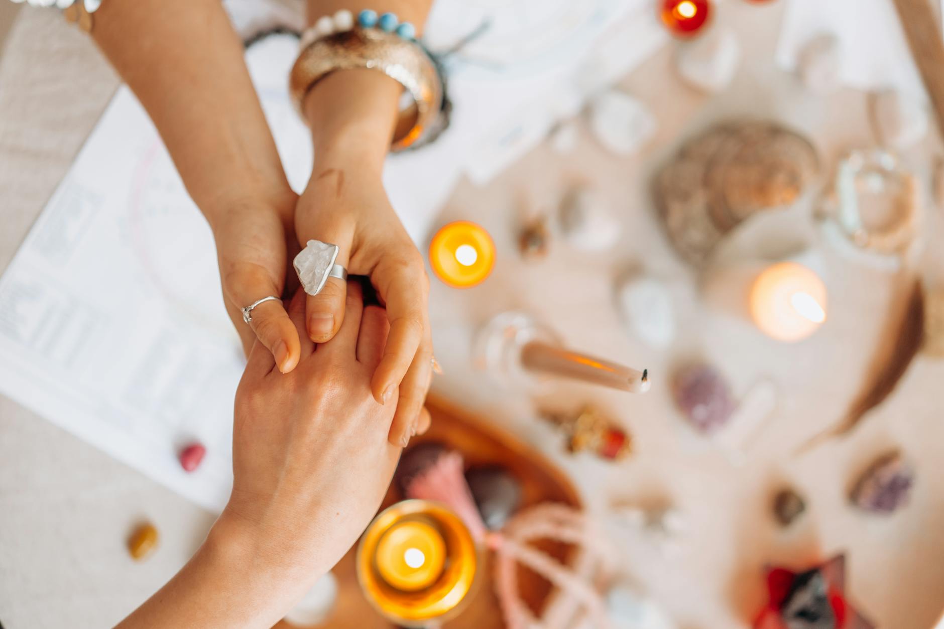 a person holding another person s hand above the table with lighted candles