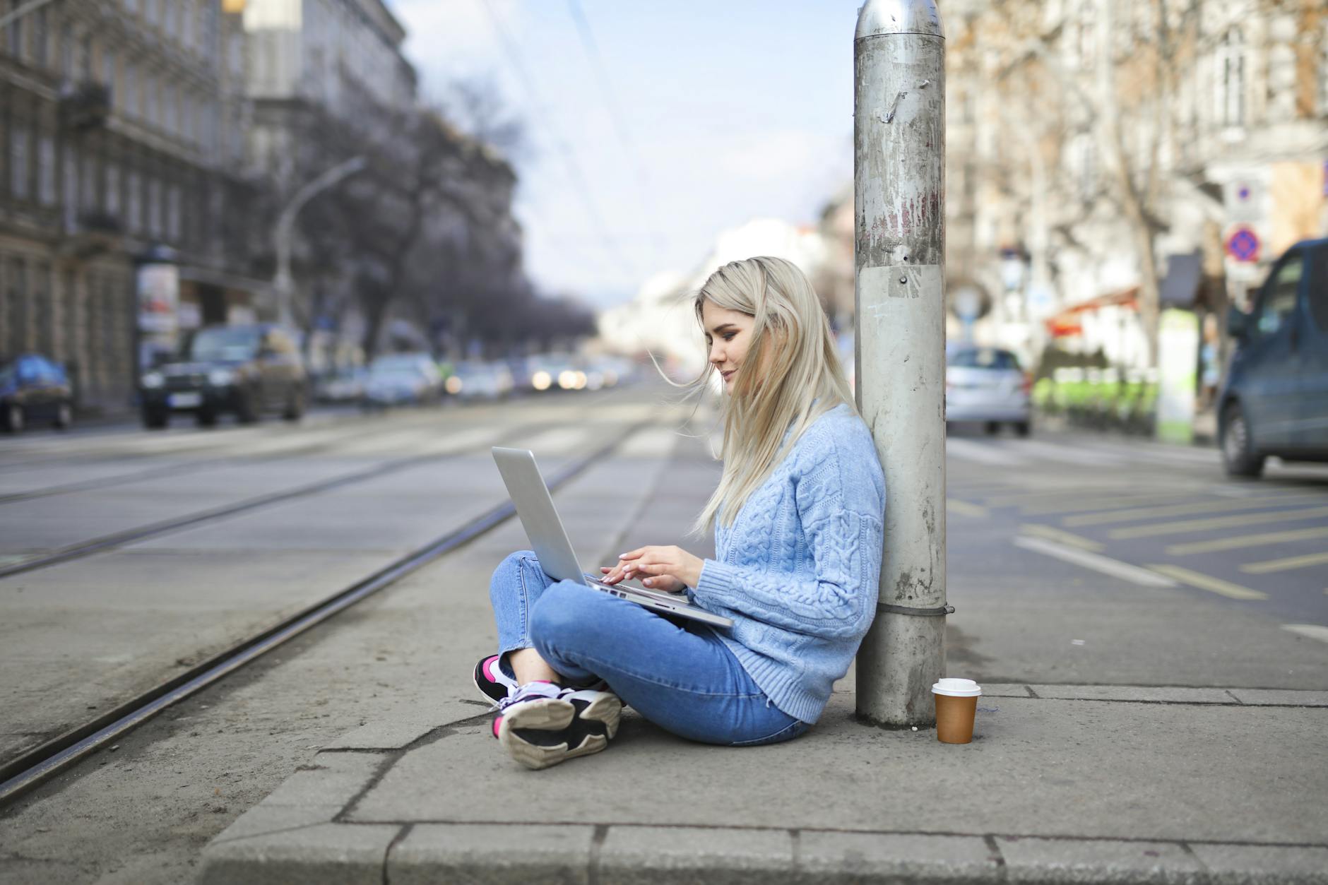 woman in blue sweater typing on computer laptop